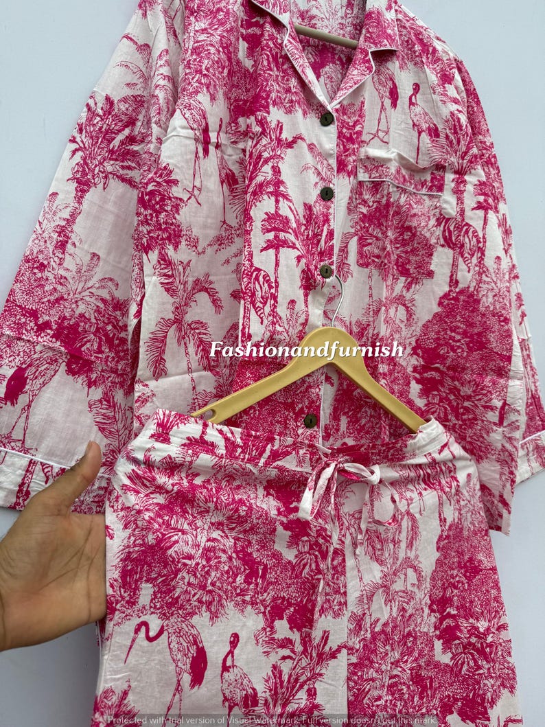 May include: A two-piece pajama set in white and fuchsia. The set features a button-down shirt with a chest pocket and shorts with a drawstring waist. The fabric is printed with a tropical scene of trees and birds. The text "Fashionandfurnish" is visible.