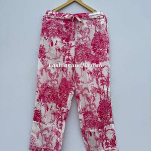 May include: White and pink pajama pants with a tropical print featuring trees, birds, and tigers. The pants have a drawstring waist and a white trim. The text "Fashionandfurnish" is visible on the pants.