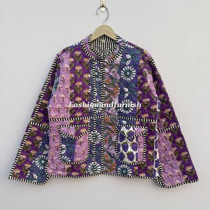 May include: A patchwork quilted jacket in shades of purple, lavender, and white, with floral and fruit patterns. It has two front pockets and a black and white striped trim. The text "Fashionandfurnish" is visible on the jacket.