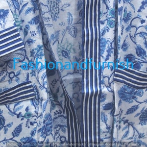 May include: A white cotton robe with a blue floral print and blue and white striped trim. The robe has a long sleeve and a tie closure.