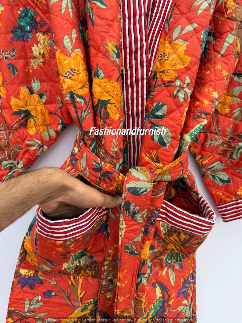 May include: A quilted, red floral robe with yellow and blue flowers. The robe has a striped interior and trim, with a matching belt and pockets. The robe is made of a soft, quilted fabric.