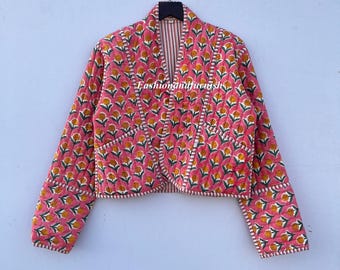 May include: A pink quilted jacket with a floral print and white trim. The jacket has a V-neck and long sleeves.