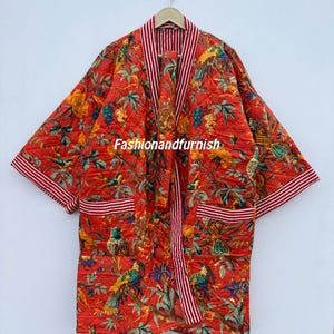 May include: A quilted red robe featuring a colourful bird and floral design. The robe has a striped trim and pockets. The text "Fashionandfurnish" is visible on the robe.