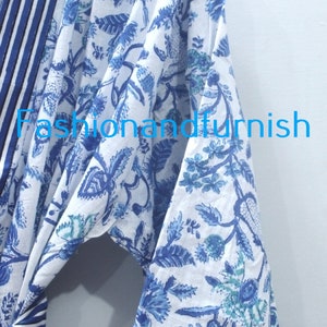 May include: A white cotton robe with a blue floral print and blue and white striped trim. The robe has a tie belt and long sleeves.