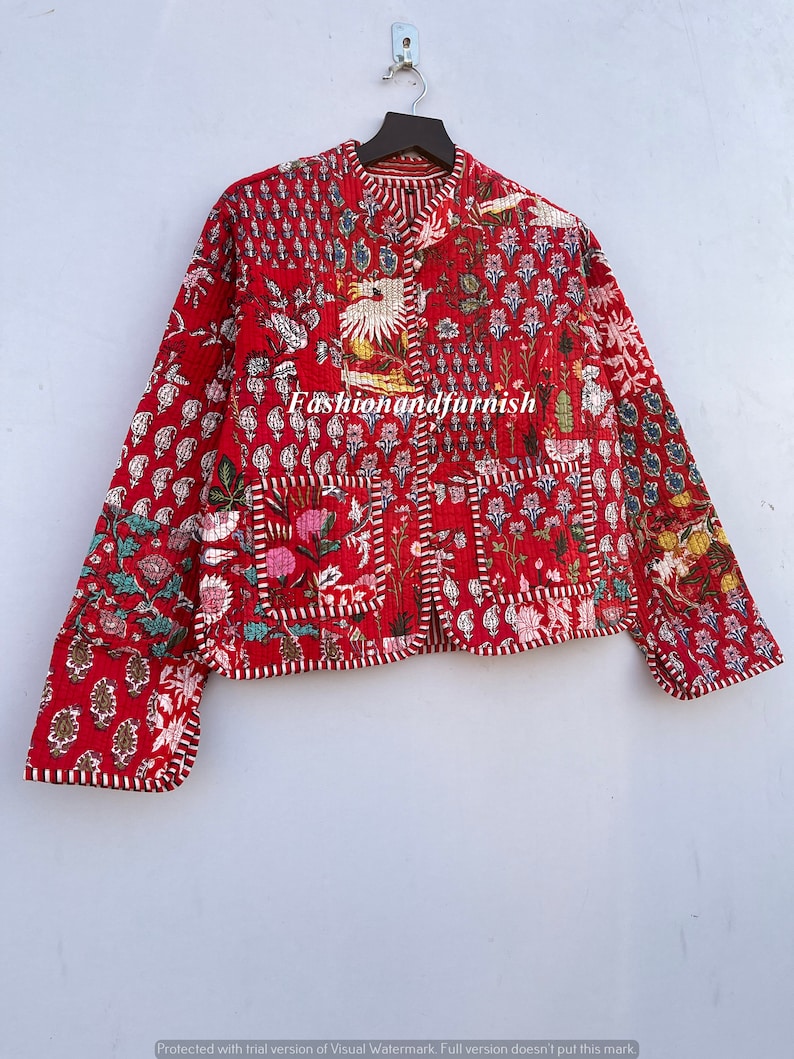 May include: A red quilted jacket with a floral print and white stitching. The jacket has a mandarin collar and a button closure. The fabric is a patchwork of different floral patterns.