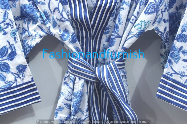 May include: A white cotton robe with blue floral print and blue and white striped trim. The robe has a tie belt and long sleeves.