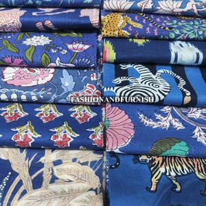 May include: An assortment of folded fabric pieces in various shades of blue. The fabrics feature floral, animal, and botanical patterns in white, pink, and tan. The text "FASHIONANDFURNISH" is visible. The fabrics are stacked together.