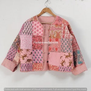 May include: A pink quilted jacket with a patchwork design featuring various floral and animal prints. The jacket has a button closure and long sleeves.