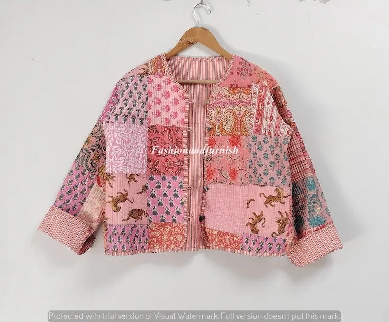 May include: A pink quilted jacket with a patchwork design featuring various floral and animal prints. The jacket has a button closure and long sleeves.