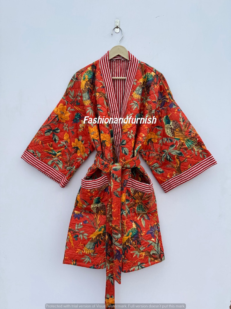 May include: A red quilted robe featuring a floral and bird design. The robe has a striped trim and a matching belt. The text "Fashionandfurnish" is visible. The robe is hanging on a wooden hanger.