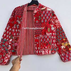 May include: Red quilted jacket with a floral print and a striped lining. The jacket has a mandarin collar and long sleeves. "Fashionandfurnish" is printed on the front of the jacket.