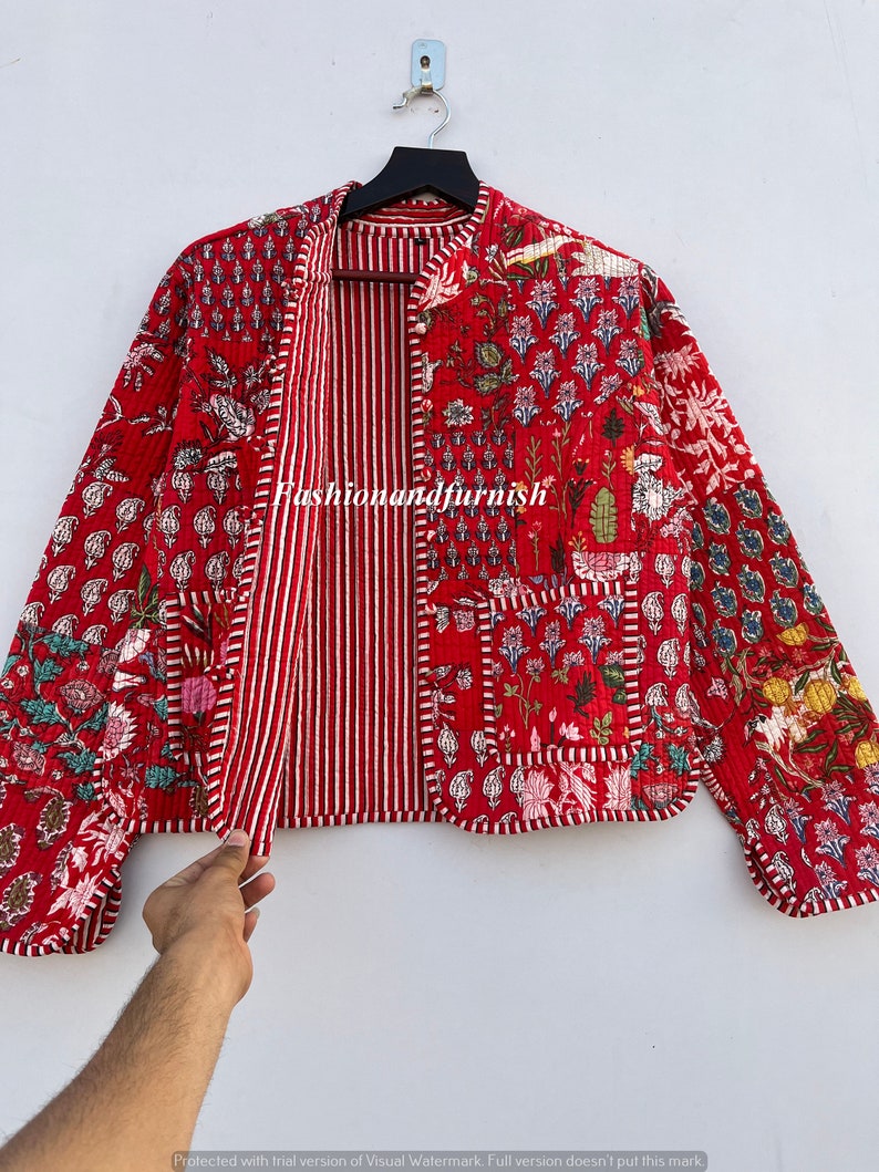 May include: Red quilted jacket with a floral print and a striped lining. The jacket has a mandarin collar and long sleeves. "Fashionandfurnish" is printed on the front of the jacket.