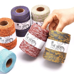 May include: A collection of colorful spools of yarn, each with a label that reads "THE XEXO 3.0". The yarn colors include orange, purple, red, yellow, green, and blue. The yarn is a mix of colors, creating a textured appearance.