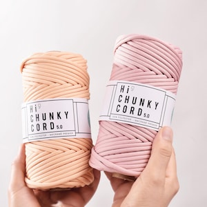 May include: Two spools of Hi9 Chunky Cord 5.0 macrame cord in peach and pink are held in hands against a white background. Each spool has a white label with black text. The cord is made of 100% polyester.