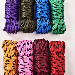 May include: Nine bundles of colorful rope in purple, olive green, blue, and green at the top, and yellow, pink, maroon, and red at the bottom. Each rope has a contrasting black pattern.