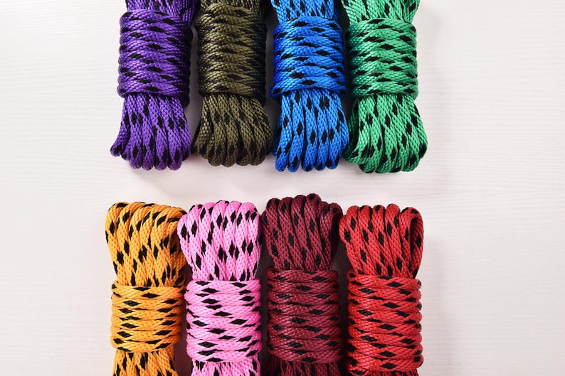 May include: Nine bundles of colorful rope in purple, olive green, blue, and green at the top, and yellow, pink, maroon, and red at the bottom. Each rope has a contrasting black pattern.