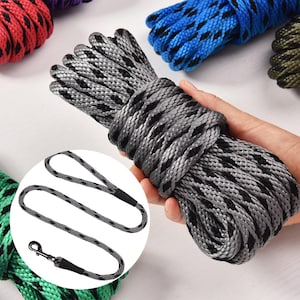 May include: A gray and black patterned rope is held in a hand, with a matching leash in a circular inset. Other ropes in red, blue, and green are visible in the background. The rope is tightly wound.