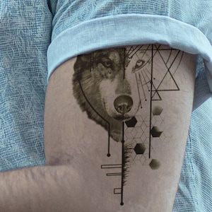 May include: A black and white wolf tattoo design with geometric shapes and lines. The tattoo is on a person's arm.