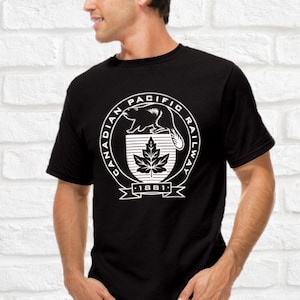 Op de afbeelding: Zwart T-shirt met een witte afbeelding van het logo van de Canadian Pacific Railway. Het logo toont een bever, een esdoornblad en de tekst "Canadian Pacific Railway 1881".