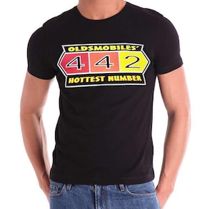 May include: A black short-sleeved t-shirt featuring a graphic print on the chest. The design includes the text OLDSMOBILES' 4 4 2 HOTTEST NUMBER in yellow, white, and black, with the numbers 4, 4, and 2 set against red, orange, and yellow backgrounds.