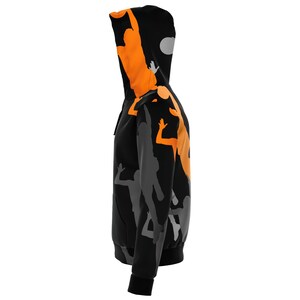 May include: Black hoodie with a print of orange and gray basketball players. The hoodie has a drawstring hood and a zipper closure.