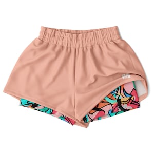 Puede incluir: Shorts deportivos de color melocotón con una capa estampada de colores debajo. Los shorts tienen una cintura elástica y un pequeño logotipo "THK" en el lado derecho.