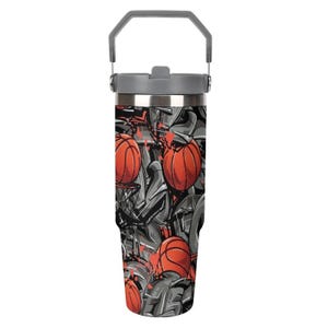 May include: A stainless steel tumbler with a gray handle and lid. The body of the tumbler is covered in a basketball-themed design with red basketballs and gray graffiti-style art. The tumbler is designed to keep drinks cold.