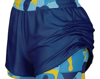 Puede incluir: Shorts deportivos de camuflaje azul y amarillo con una capa exterior azul marino. Los shorts tienen un forro de malla y una cintura con cordón.