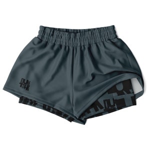 May include: Dark teal athletic shorts with an elasticated waistband. The shorts have a built-in liner with a black graphic print. The text "RUN TALK" is printed in black on the left leg.