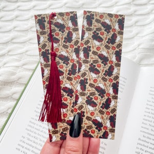 May include: Two brown bookmarks with a red tassel. The bookmarks feature a repeating pattern of a train, luggage, and other Harry Potter themed icons.