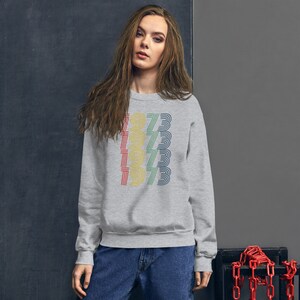 May include: A gray sweatshirt with a vintage-style graphic of the year 1973 repeated five times in rainbow colors.