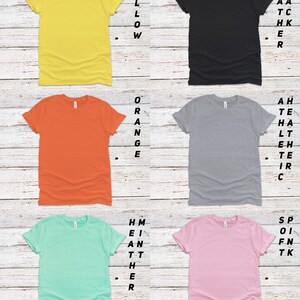 May include: Six different colored t-shirts with rolled up sleeves. The colors are yellow, orange, gray, light blue, pink, and black. The text "More colors available. PM for details." is at the bottom of the image.