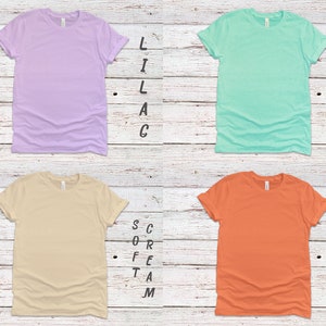 May include: Four blank t-shirts in different colors: lilac, teal, beige, and orange. The shirts are arranged in a grid pattern on a white wood background. The text "Lilac", "Heather", "Soft Cream", and "Sunset" are written vertically next to each shirt.