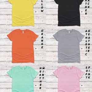 K&ouml;nnte beinhalten: Sechs T-Shirts in verschiedenen Farben mit hochgekrempelten &Auml;rmeln. Die Farben sind Gelb, Orange, Grau, Hellblau, Rosa und Schwarz. Der Text "Mehr Farben verf&uuml;gbar. PN f&uuml;r Details." befindet sich am unteren Rand des Bildes.