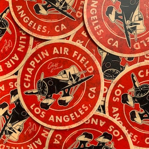 May include: A collection of round red stickers with a vintage airplane design. The stickers feature the text "CHAPLIN AIR FIELD LOS ANGELES, CA" in a circular layout, with a distressed, aged look.
