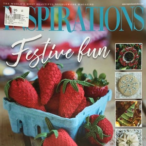 May include: A magazine cover titled "Inspirations" with the words "Festive fun". The image shows a blue punnet filled with red, stitched strawberries. The text "stitch THESE BRIGHT BERRIES" is also visible.