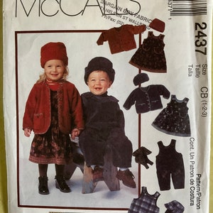 May include: A McCall's sewing pattern for children's outfits, including a red jacket and dress, a dark blue jumpsuit, and other garments. The pattern features the text "COZY TOGS" and the number "2437".