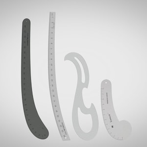 Puede incluir: Cuatro tipos diferentes de reglas, que incluyen una regla curva, una curva francesa y dos reglas rectas. Las reglas son todas de plástico y tienen marcas negras.