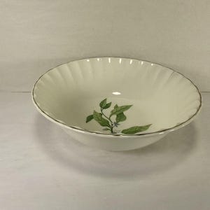Peut inclure: Un saladier en céramique blanche avec un motif cannelé et un bord doré. Le bol présente un motif floral vert et bleu à l'intérieur. Ce bol décoratif convient pour servir des salades ou d'autres plats.