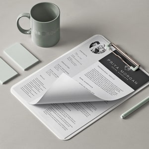 K&ouml;nnte beinhalten: Ein wei&szlig;er Lebenslauf auf einem Clipboard mit einer schwarzen Kopfzeile, die "PRIYA MORGAN SALES ASSOCIATE" und ein professionelles Profil lautet. Der Lebenslauf ist teilweise umgeklappt, wodurch die Abschnitte F&auml;higkeiten und Berufserfahrung sichtbar werden. Ein gr&uuml;ner Stift und zwei kleine gr&uuml;ne Haftnotizen liegen auf dem Tisch neben dem Clipboard.