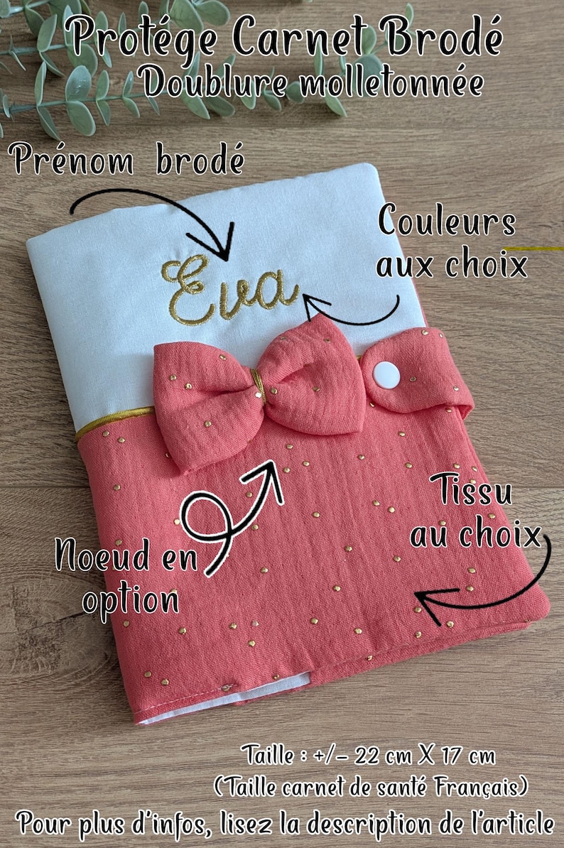 May include: Embroidered baby book cover with the name "Eva" in gold thread. The cover has a pink bow and measures approximately 22 cm x 17 cm. The design includes options for fabric and colours. The cover is padded.