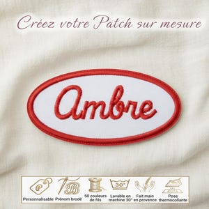 Peut inclure: Un écusson brodé de forme ovale avec un centre blanc et une bordure rouge. Le prénom Ambre est brodé en écriture cursive rouge au centre. Au-dessus, le texte indique Créez votre Patch sur mesure. En bas, des icônes illustrent la personnalisation, le nom brodé, les 50 couleurs de fils, le lavage à 30 degrés, le fait main et la pose thermocollante.
