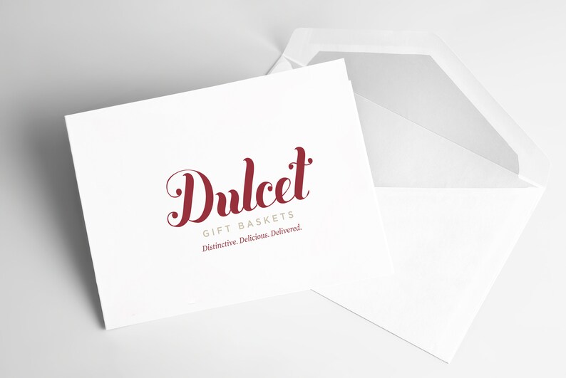 May include: A white card with a red cursive logo that says "Dulcet Gift Baskets" and the tagline "Distinctive. Delicious. Delivered."