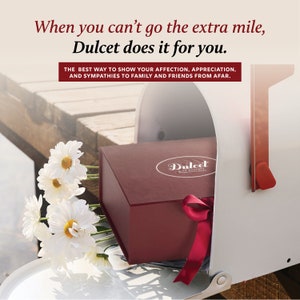 May include: A red gift box with a white ribbon and a white label that says "Dulcet" is being placed in a white mailbox. The box is surrounded by white daisies.