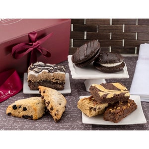 May include: A gift box filled with assorted baked goods, including chocolate chip scones, brownies, and chocolate-covered cookies. The box is tied with a burgundy ribbon.