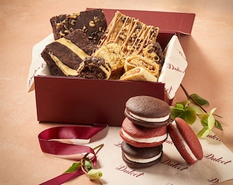 May include: A red box filled with assorted chocolate chip cookies and brownies, with a stack of chocolate and red velvet macarons on a white background with the word "Dulcet" printed on it.
