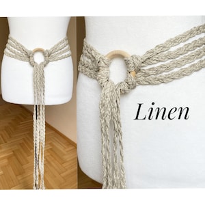 May include: A beige linen rope belt with a wooden ring closure. The belt is tied in a knot and has long tassels. The word "Linen" is written in black text on the right side of the image.