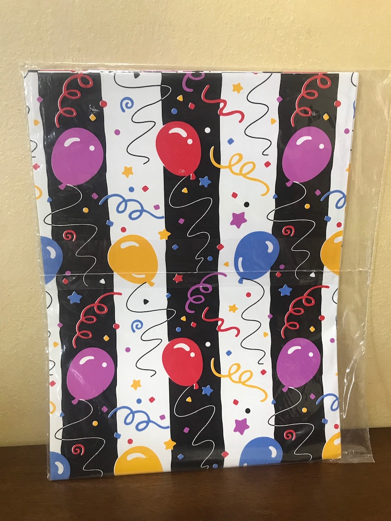 May include: A sheet of white wrapping paper with black stripes and a repeating pattern of colorful balloons, confetti, and curly ribbons.
