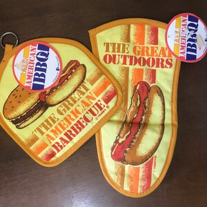 May include: Two yellow and orange pot holders with a hot dog and hamburger design. The text on the pot holders reads "The Great American Barbecue" and "The Great Outdoors".