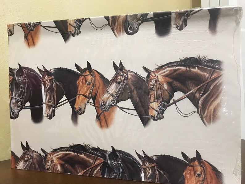 May include: A white background with a repeating pattern of brown and black horses with bridles. The horses are facing left and right, and their heads are tilted in different directions.
